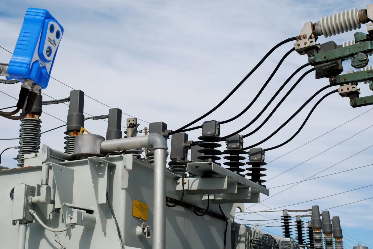 Electrical transformer with cables under cloudy sky.