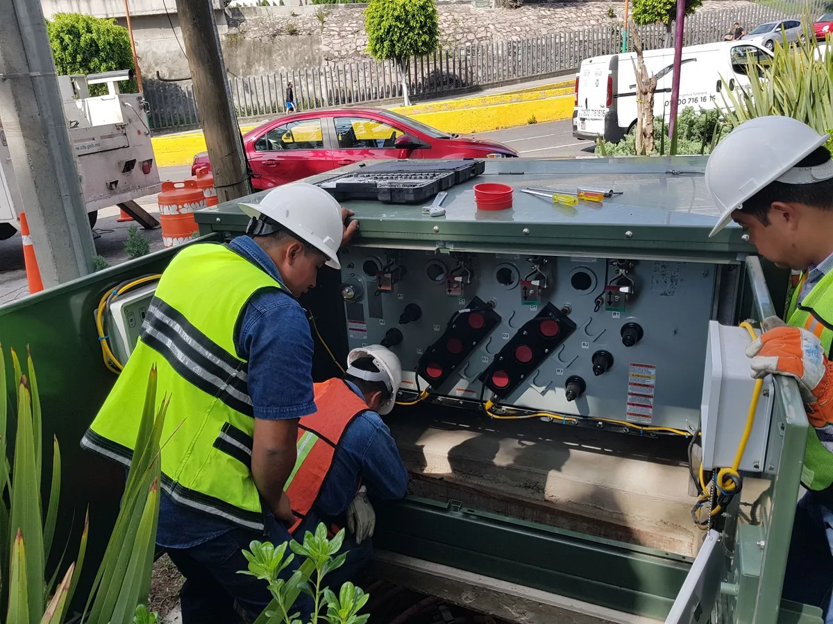 Workers inspecting electrical equipment outdoors.