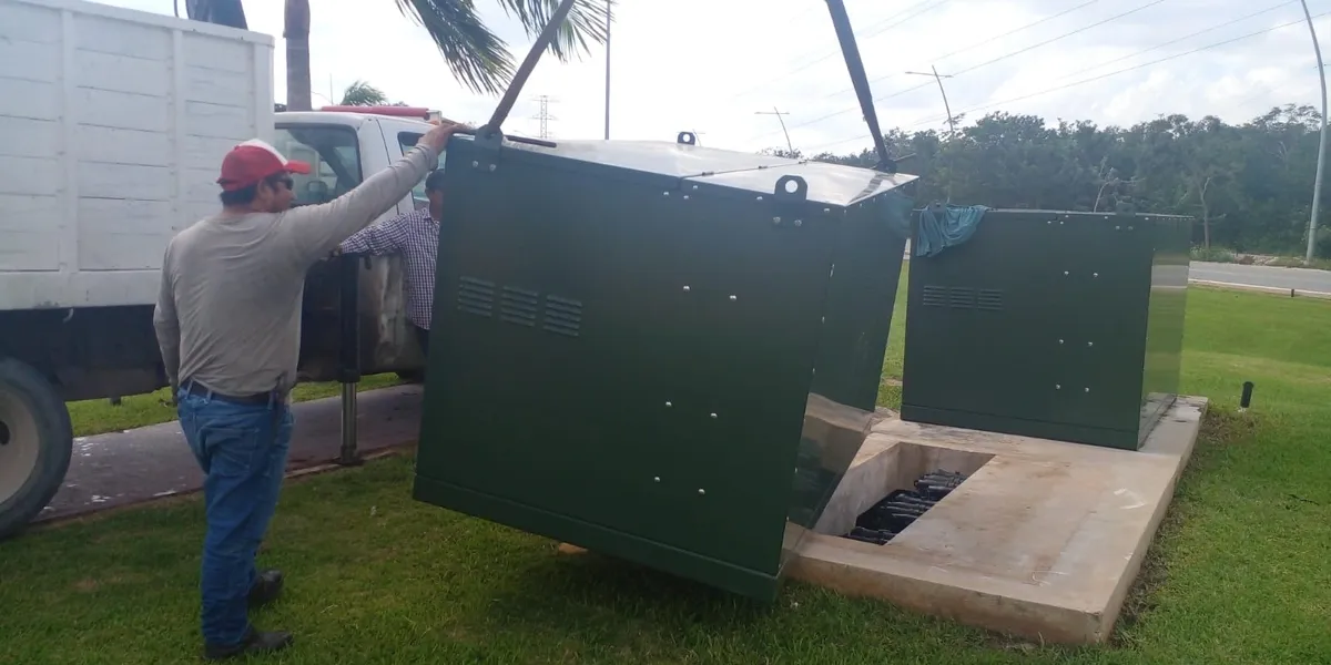 Workers installing large green electrical box.