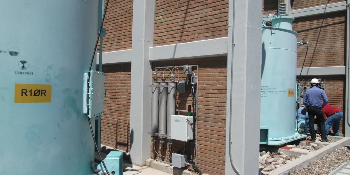 Workers near industrial equipment outside brick building.
