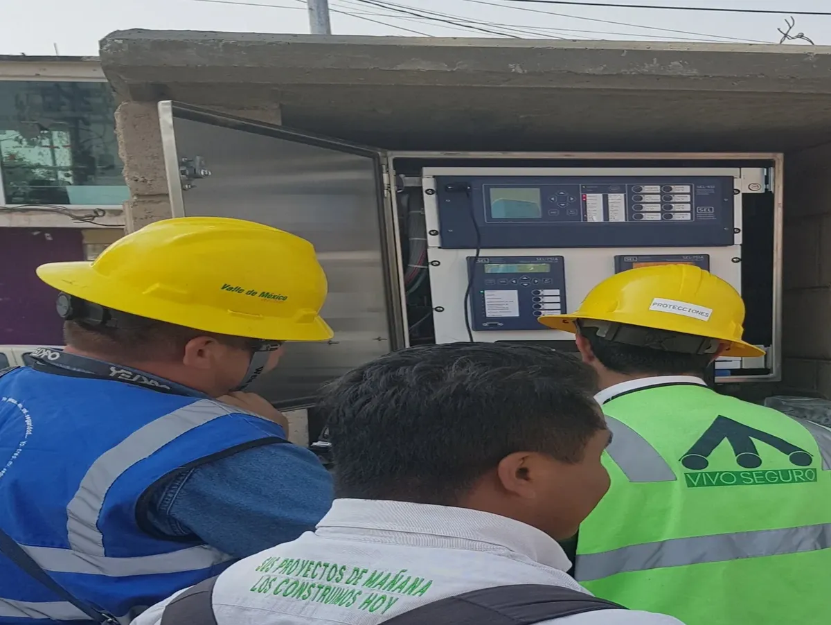 Workers inspecting electrical control panel outdoors.