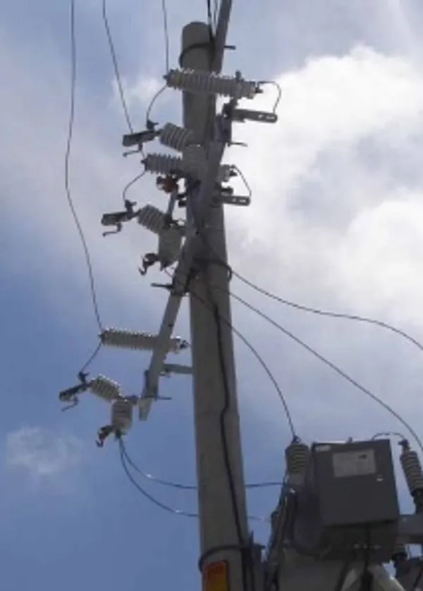 Electric pole with wires against cloudy sky.