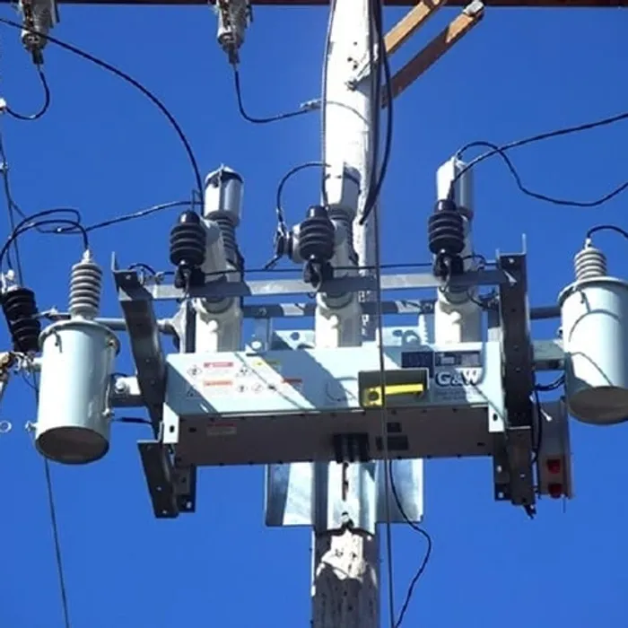 Utility pole transformer against clear blue sky.