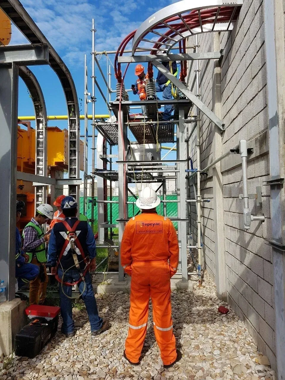 Construction workers on scaffolding at industrial site.